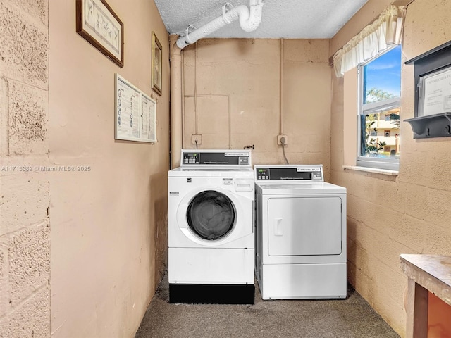 laundry room featuring washing machine and clothes dryer and a textured ceiling