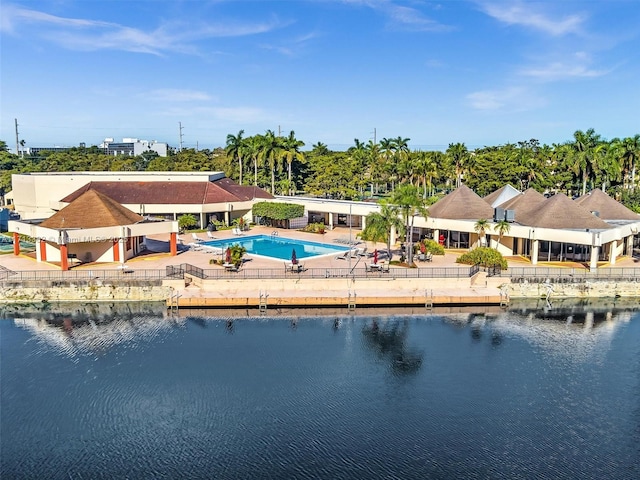 rear view of property featuring a water view, a community pool, and a patio area