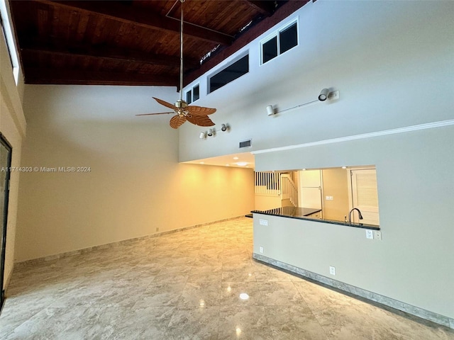 unfurnished living room featuring beamed ceiling, a high ceiling, ceiling fan, and wood ceiling