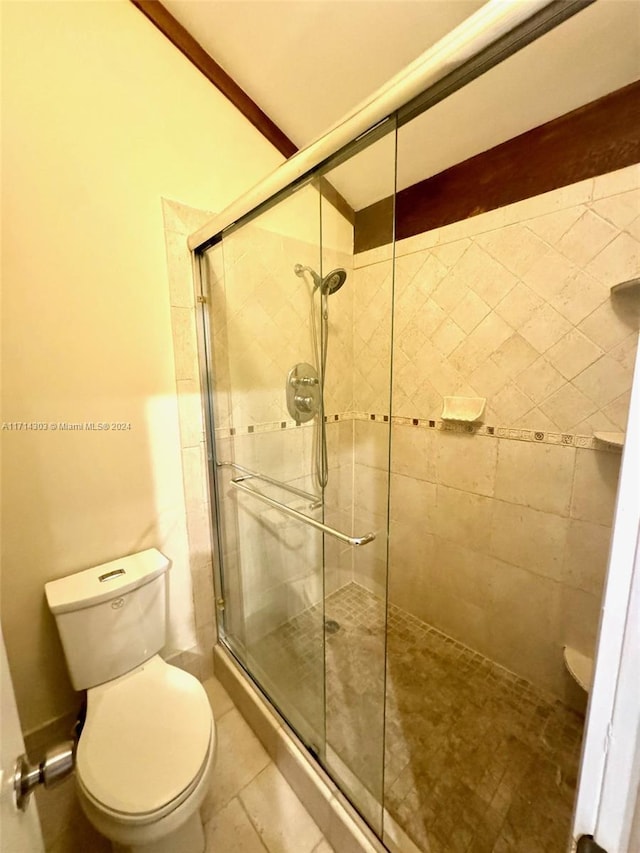 bathroom featuring tile patterned flooring, toilet, and walk in shower