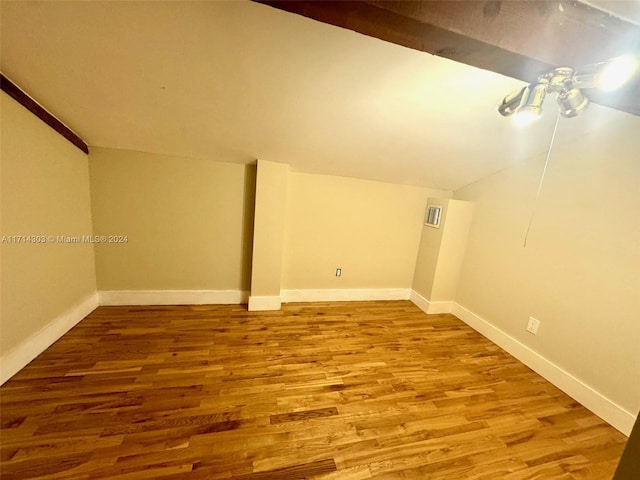 additional living space with hardwood / wood-style floors and vaulted ceiling