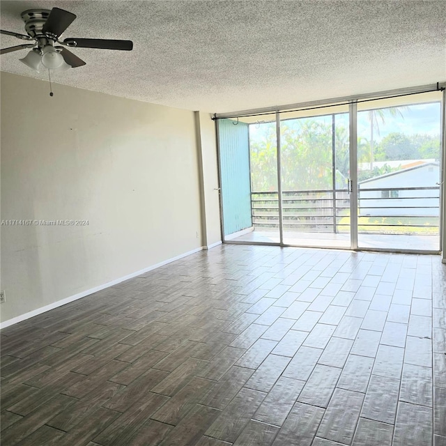 empty room with floor to ceiling windows, ceiling fan, and a textured ceiling