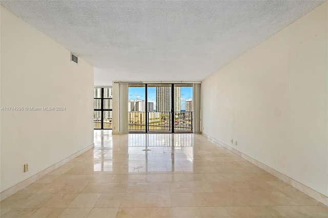 unfurnished room featuring a textured ceiling and a wall of windows