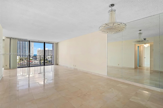 empty room featuring floor to ceiling windows, a chandelier, and a textured ceiling