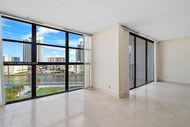 unfurnished room featuring expansive windows and a water view