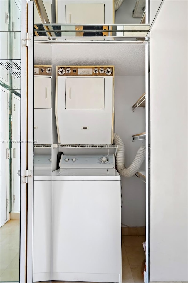 washroom with tile patterned flooring and stacked washer and dryer