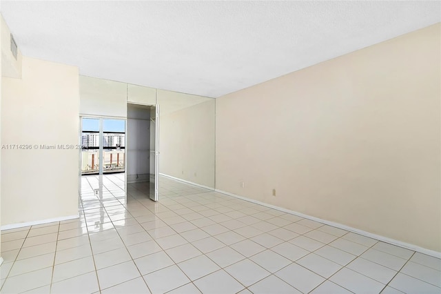 spare room featuring expansive windows and light tile patterned floors