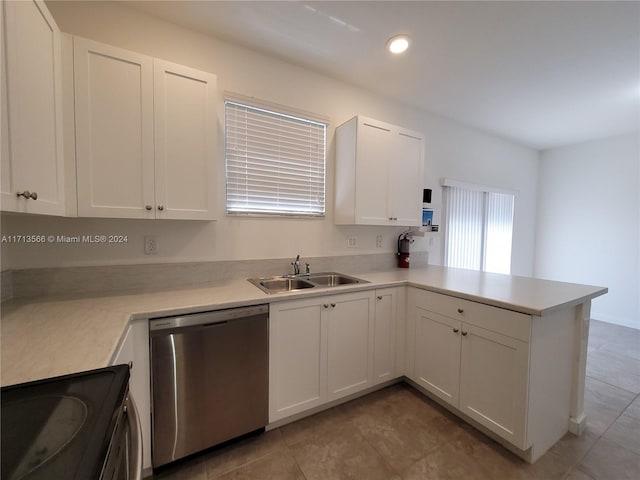 kitchen with kitchen peninsula, stainless steel dishwasher, sink, range, and white cabinetry