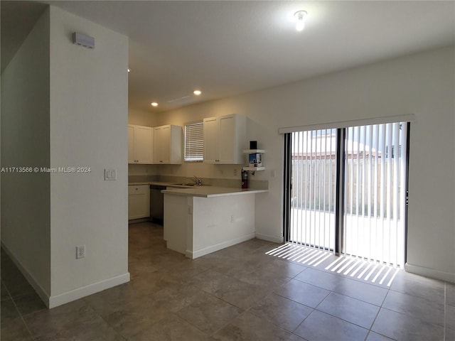 kitchen featuring kitchen peninsula, stainless steel dishwasher, light tile patterned floors, white cabinets, and a breakfast bar area