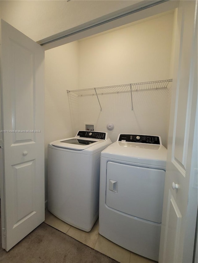 clothes washing area featuring washing machine and dryer and tile patterned flooring