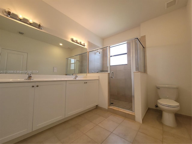 bathroom featuring tile patterned floors, a shower with door, vanity, and toilet