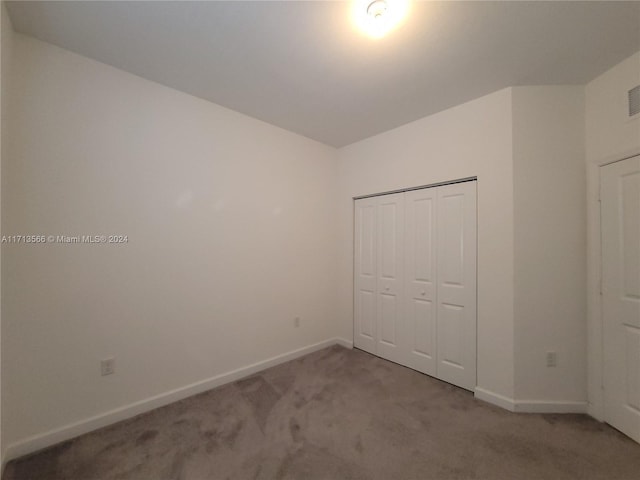 unfurnished bedroom featuring light carpet and a closet