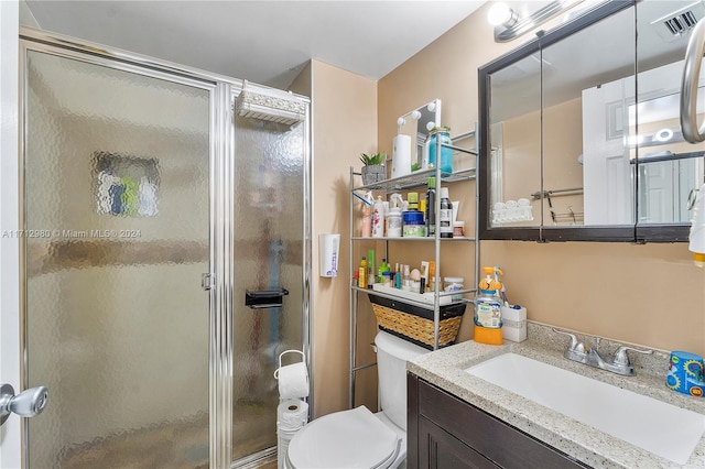 bathroom with a shower with door, vanity, and toilet