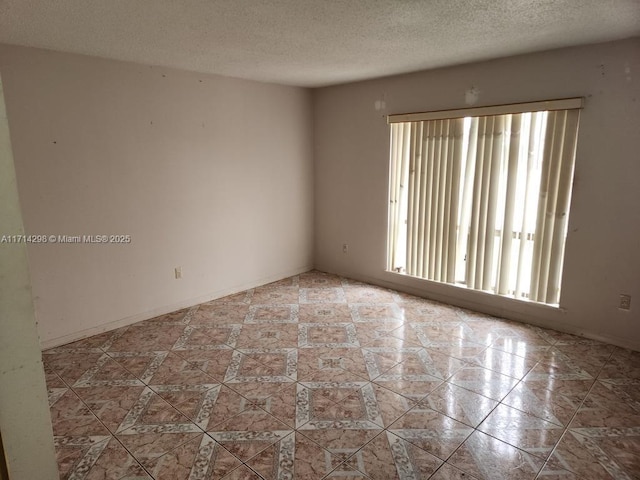 tiled empty room with a textured ceiling