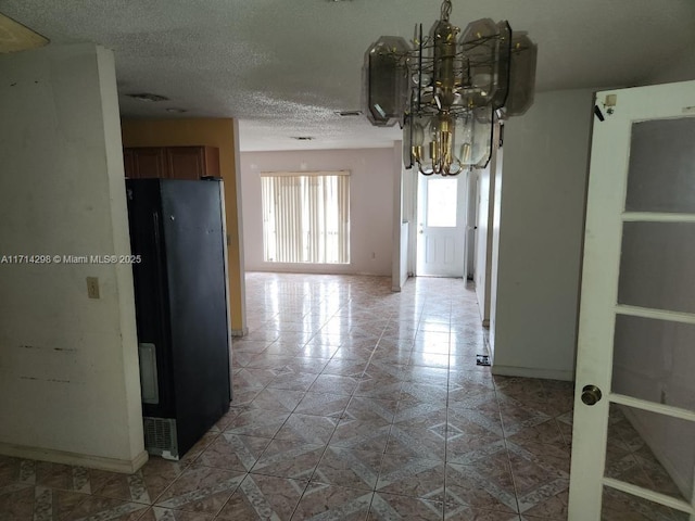 unfurnished dining area with a chandelier and a textured ceiling