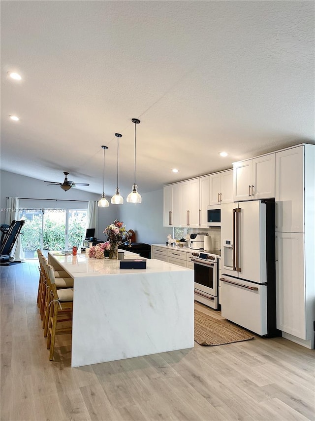 kitchen with a center island, light hardwood / wood-style flooring, pendant lighting, white appliances, and white cabinets