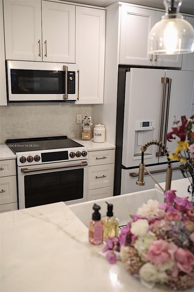 kitchen featuring white cabinetry, light stone counters, and appliances with stainless steel finishes