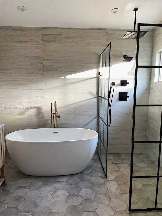 bathroom featuring separate shower and tub, tile patterned flooring, vanity, and tile walls