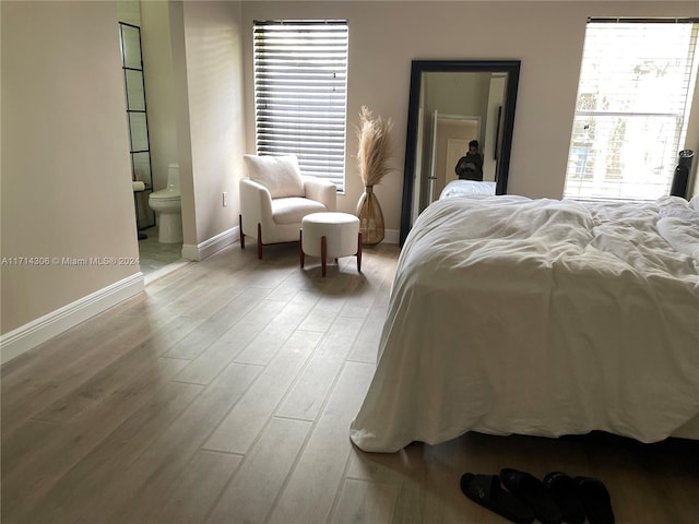 bedroom with light hardwood / wood-style flooring, connected bathroom, and multiple windows