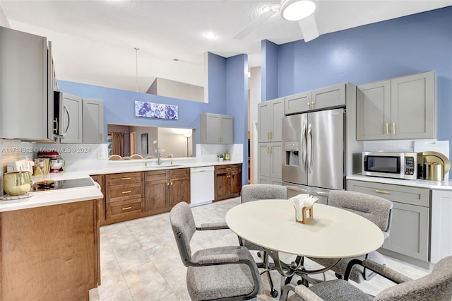 kitchen featuring appliances with stainless steel finishes, backsplash, gray cabinets, and a high ceiling