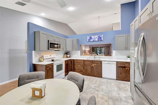 kitchen featuring tasteful backsplash, stainless steel appliances, sink, gray cabinets, and lofted ceiling