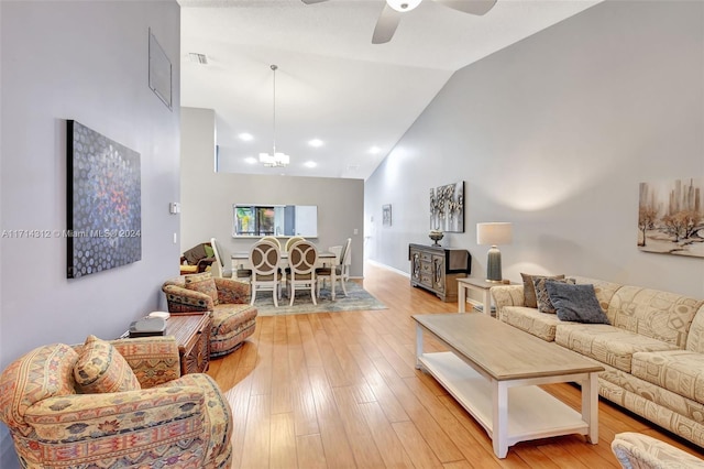 living room with high vaulted ceiling, light hardwood / wood-style floors, and ceiling fan with notable chandelier