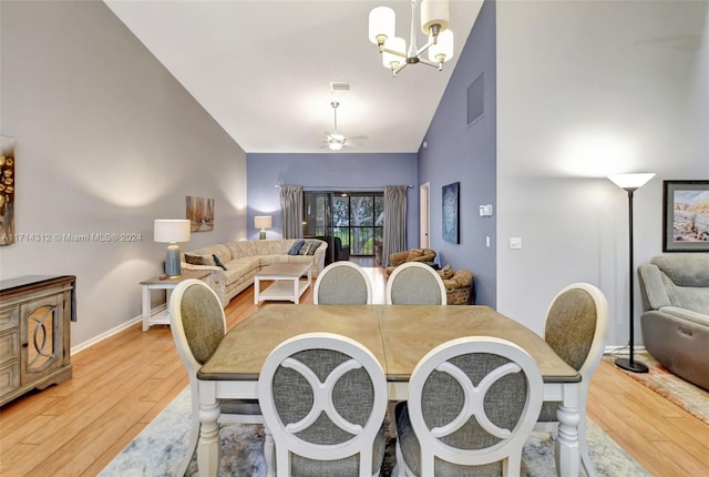 dining area featuring wood-type flooring, ceiling fan with notable chandelier, and lofted ceiling