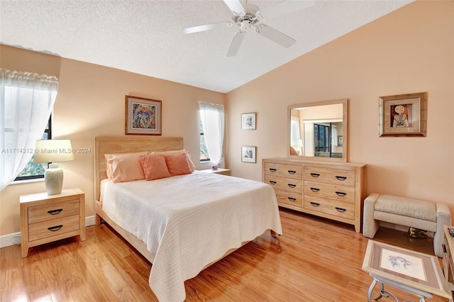 bedroom with ceiling fan, light hardwood / wood-style floors, a textured ceiling, and vaulted ceiling