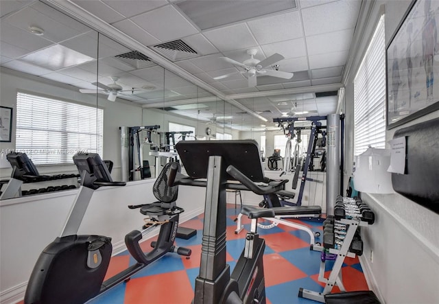 gym with a paneled ceiling, ceiling fan, and plenty of natural light