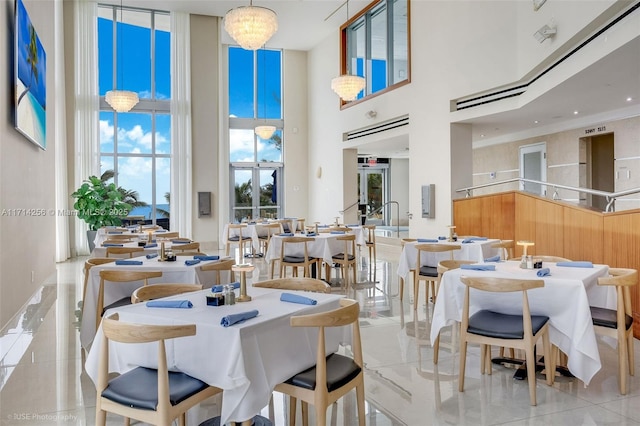 dining area with an inviting chandelier and a towering ceiling