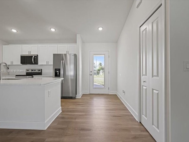 kitchen with sink, white cabinetry, light hardwood / wood-style flooring, and stainless steel appliances