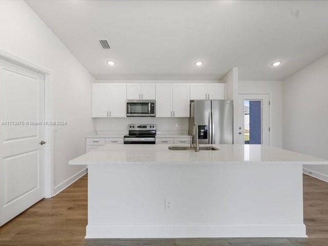 kitchen with stainless steel appliances, white cabinetry, sink, and an island with sink