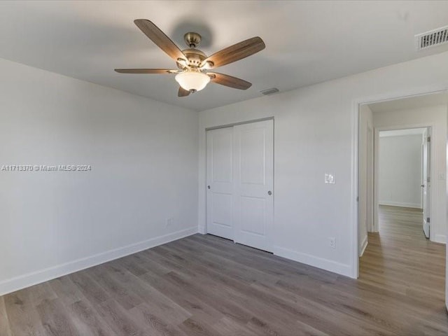 unfurnished bedroom featuring ceiling fan, a closet, and hardwood / wood-style floors