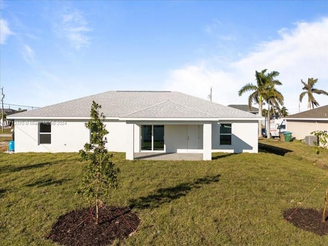 rear view of property featuring a yard, central air condition unit, and a patio