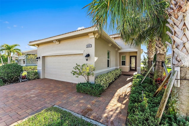 view of home's exterior featuring decorative driveway, an attached garage, and stucco siding