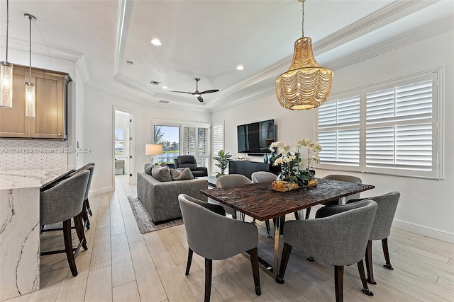 dining area with ceiling fan, a raised ceiling, ornamental molding, and light hardwood / wood-style flooring