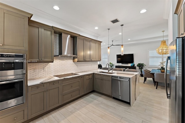 kitchen with kitchen peninsula, stainless steel appliances, sink, wall chimney range hood, and pendant lighting