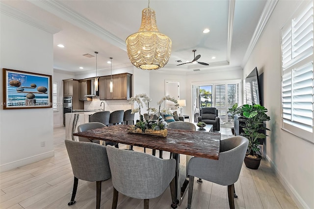 dining space featuring a raised ceiling, light hardwood / wood-style flooring, ceiling fan, and ornamental molding