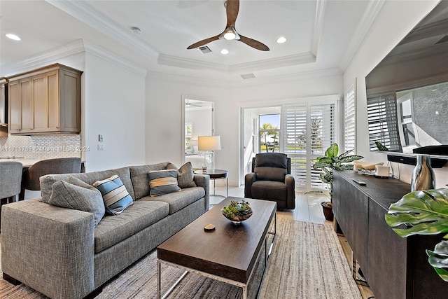 living room featuring a tray ceiling, light hardwood / wood-style flooring, ceiling fan, and ornamental molding