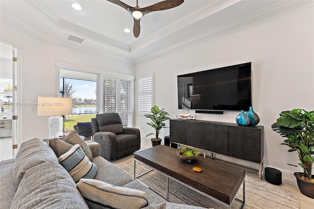 living room with light hardwood / wood-style floors, a raised ceiling, ceiling fan, and ornamental molding