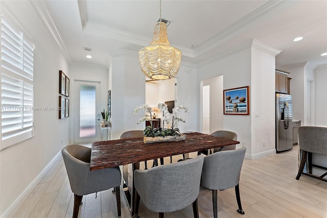 dining room featuring a tray ceiling, an inviting chandelier, light hardwood / wood-style floors, and ornamental molding