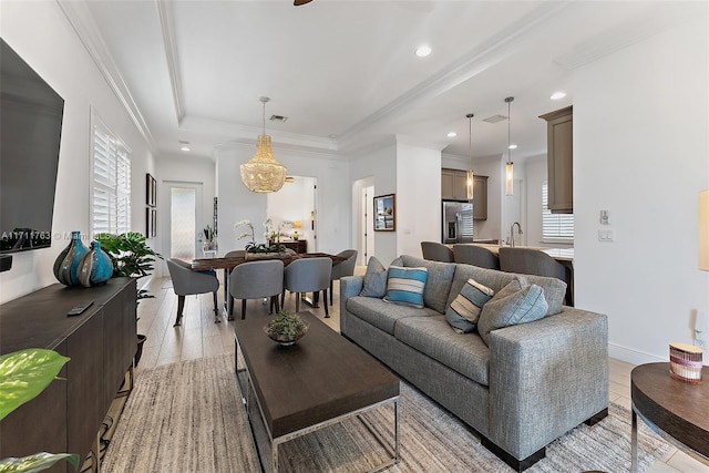 living room with a raised ceiling, crown molding, light hardwood / wood-style flooring, and sink