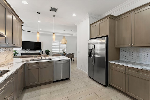 kitchen with kitchen peninsula, tasteful backsplash, stainless steel appliances, sink, and hanging light fixtures