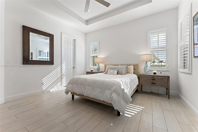 bedroom featuring a tray ceiling, light hardwood / wood-style flooring, and ceiling fan