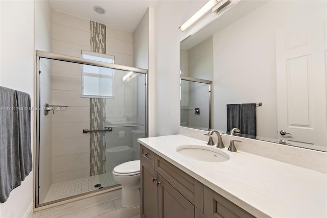 bathroom featuring an enclosed shower, vanity, and toilet