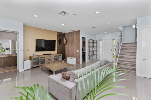 living room with a textured ceiling, tile patterned floors, and wooden walls