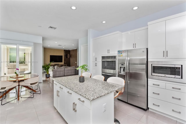 10410 Ranchette Dr, Cooper City, FL 33328 - kitchen with stainless steel appliances, a kitchen island, light tile patterned floors, light stone countertops, and recessed lighting