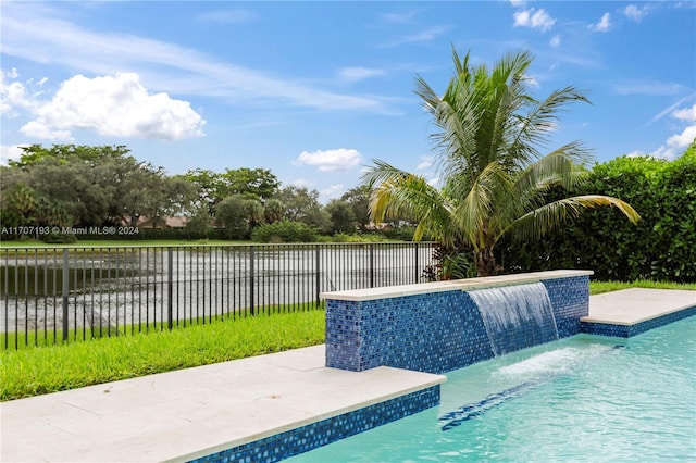 view of swimming pool featuring pool water feature and a water view