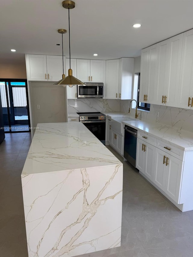 kitchen with white cabinetry, sink, a center island, pendant lighting, and appliances with stainless steel finishes