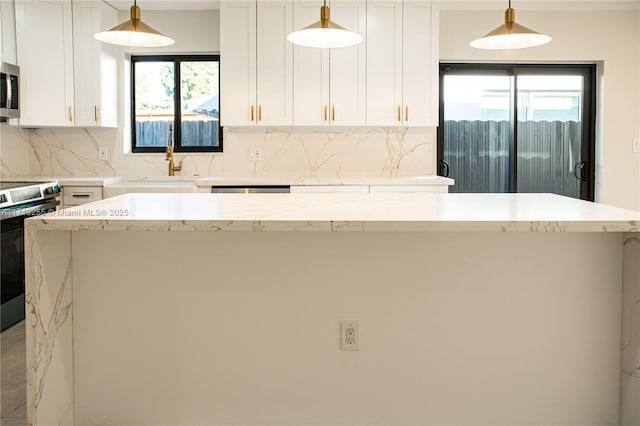 kitchen with appliances with stainless steel finishes, a center island, white cabinetry, and hanging light fixtures